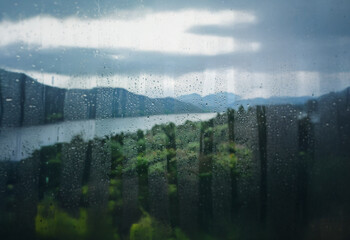 Poster - A view of a lake and mountains through a rain-streaked window.