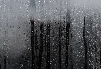 Poster - A close-up view of a window pane covered in condensation and water droplets.