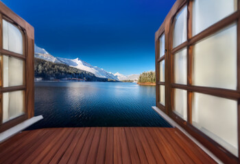 Poster - Open wooden windows frame a view of a lake with snow-capped mountains in the distance. The wooden deck floor stretches towards the water.
