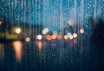 Aufkleber - A blurred view of city lights through a rain-streaked window.