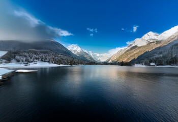 Poster - A serene mountain lake with snow-capped peaks reflecting in the still water.