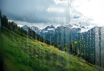 Poster - A view of a mountain range through a rain-streaked window.