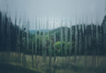 Aufkleber - A blurry view of a landscape through a window covered in condensation.