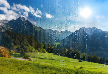 Poster - A view of a mountain range through a window with raindrops.