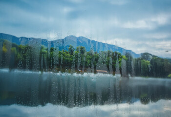 Poster - A view of a lake and mountains through a window with condensation.