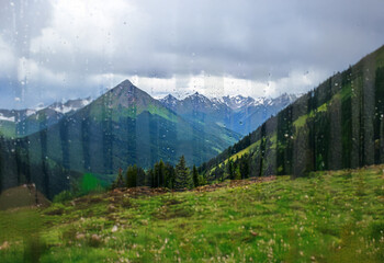 Poster - A view of a mountain range through a window with raindrops on the glass.
