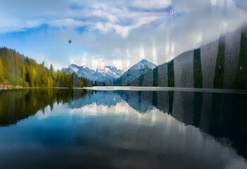 Poster - A tranquil mountain lake scene with snow-capped peaks reflecting in the water.
