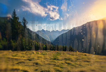 Poster - A mountain range viewed through a window with raindrops.