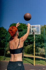 close up sports ground basketball field active recreation girl with short hair in shorts and black T-shirt trains to throw basketball into the hoop training in agility