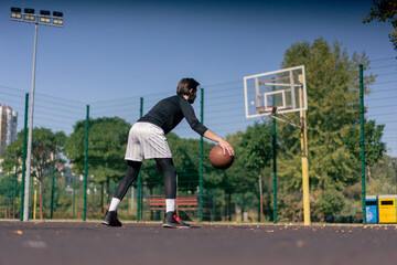 a sports ground basketball field active recreation guy in white shorts and black t-shirt plays basketball on camera different tricks