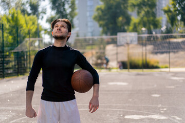 a sports ground basketball field active recreation guy in white shorts and black t-shirt stands with ball in hands posing in front of camera