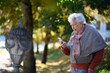 © Halfpoint - Elderly woman in the park, holding a smartphone and reading message.