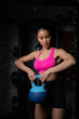 © kamonrat - Fit Woman Lifting Kettlebell During Workout Session in Gym, Focused on Strength Training and Building Muscle in a Controlled Fitness Environment