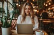 © Kishan - Businesswoman working remotely with laptop and smartphone in a coffee shop, Generative AI