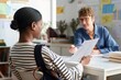 © Mediaphotos - African American woman consulting with career advisor in office setting, engaging in conversation and holding document detailing potential opportunities