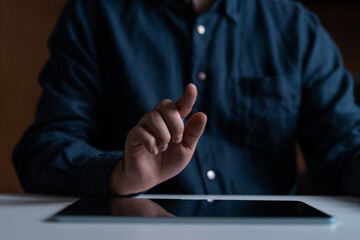 Fototapete - Close-up of hand interacting with tablet screen in a dimly lit environment.