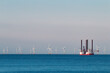 © Igor Hotinsky - Jack up wind turbines installation vessel in the sea, with wind farm on the background.