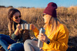 © Zoran Zeremski - Two women sitting at top of the hill at meadow resting after hiking while drinking tea.
