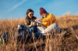 © Zoran Zeremski - Two women sitting at top of the hill at meadow resting after hiking while drinking tea.