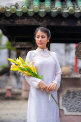 Vietnamese girl with Ao Dai dress standing in temple in Ho Chi Minh city, Vietnam. Ao dai is famous traditional costume for woman in Vietnam