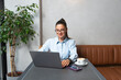 © Srdjan - One young businesswoman sitting in cafeteria taking a coffee break while working online on laptop computer. Business female professional occupation e-commerce and remotely finance and economy research