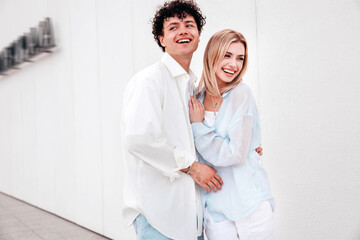 Wall Mural - Smiling beautiful woman and her handsome boyfriend. Couple in casual summer clothes. Happy cheerful family. Female and man having fun. They posing in the street in sunny day. Having tender moments