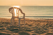 © Bits and Splits - Broken plastic chair on a sandy beach in summer morning