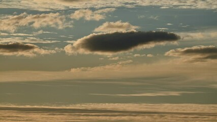 Wall Mural - time lapse of late day clouds moving at different speeds in a pale blue sky