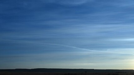 Wall Mural - time lapse of late day streaky clouds in a blue sky above a flat prairie landscape