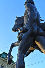 famouse horse sculpture against blue sky: The Horse Tamers, designed by the Russian sculptor, Baron Peter Klodt von Urgensburg. Anichkov bridge, Saint-Petersburg, Russia