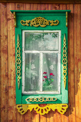 Old houses. Carved window frames. View of a fragment of a house wall with carved decorations around the window and doors. Traditional Russian old houses. Close-up. Front view. Landscape.