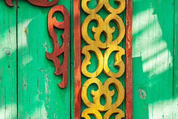 Wall Mural - Old houses. Carved window frames. View of a fragment of a house wall with carved decorations around the window and doors. Traditional Russian old houses. Close-up. Front view. Landscape.