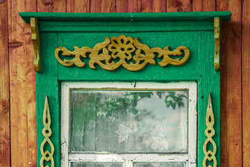 Wall Mural - Old houses. Carved window frames. View of a fragment of a house wall with carved decorations around the window and doors. Traditional Russian old houses. Close-up. Front view. Landscape.