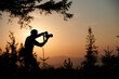 © Василь Івасюк - Silhouette of a photographer in the mountains taking pictures at dawn. Tourist holding camera on the mountain hill on sunrise background. Man takes photo of mountain in the rays of the setting sun.