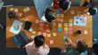 © InfiniteFlow - Top down aerial view of business team brainstorming idea and writing plan at colorful sticky notes. Professional project manager planning strategy while stick paper at meeting table. Convocation.