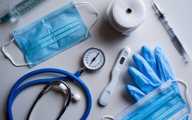 Medical supplies and equipment including face masks, stethoscope, gloves, thermometer, syringes, and bandages on a white background.