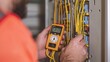© saichon - Close-up on multimeter and yellow wires in electrical panel, electricians hands at work, HD sharpness