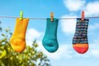 © WinThing - Colorful socks hanging on a clothesline, sunny day with blue sky and clouds.