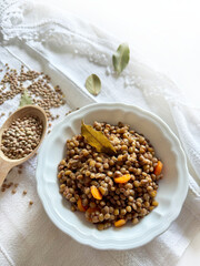 Lenticchie stufate fatte in casa aromatizzate con erbe e lenticchie crude isolate su un tavolo bianco. Cibo sano e vegetariano. Direttamente sopra.