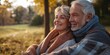 © StockUp - Elderly couple wrapped in scarves and coats enjoying warmth and affection in an autumn park at sunset.