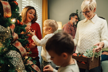 Wall Mural - Happy family decorating christmas tree with ornaments at home