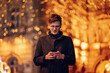 © Zamrznuti tonovi - A cheerful man is texting on street at new year's eve.