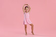 © New Africa - Little ballerina practicing dance moves on pink background