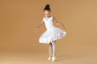 © New Africa - Little ballerina practicing dance moves on beige background