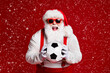 © deagreez - Portrait of his he attractive cheerful cheery ecstatic fat white-haired Santa holding in hands soccer ball having fun isolated bright vivid shine vibrant red burgundy maroon color background