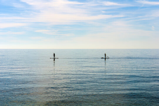 paisaje marino con dos deportistas practicando padel surf