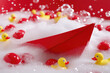© Konstiantyn Zapylaie - Red paper boat and yellow rubber ducks in bubbly foam with floating red balls
