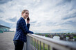 © Scopio - Business woman talking on cellphone standing at a balcony railing