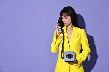 Wall Mural - Woman in yellow jacket with corded telephone on purple background, space for text