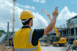 © Dzmitry - Worker signaling crane operator at construction site under bright sky